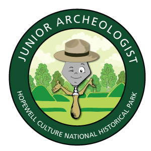 A caricature trowel winking inside of a green circle that reads Junior Archeologist
