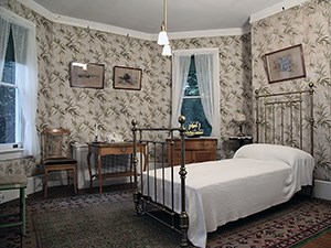 A room with bamboo printed wallpaper and a brass bed.