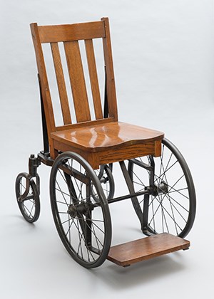 A wooden side chair mounted on metal wheels.