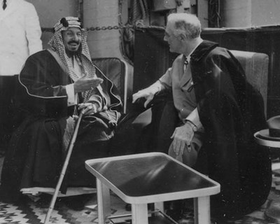 FDR seated with Ibn Saud on the deck of a large boat.