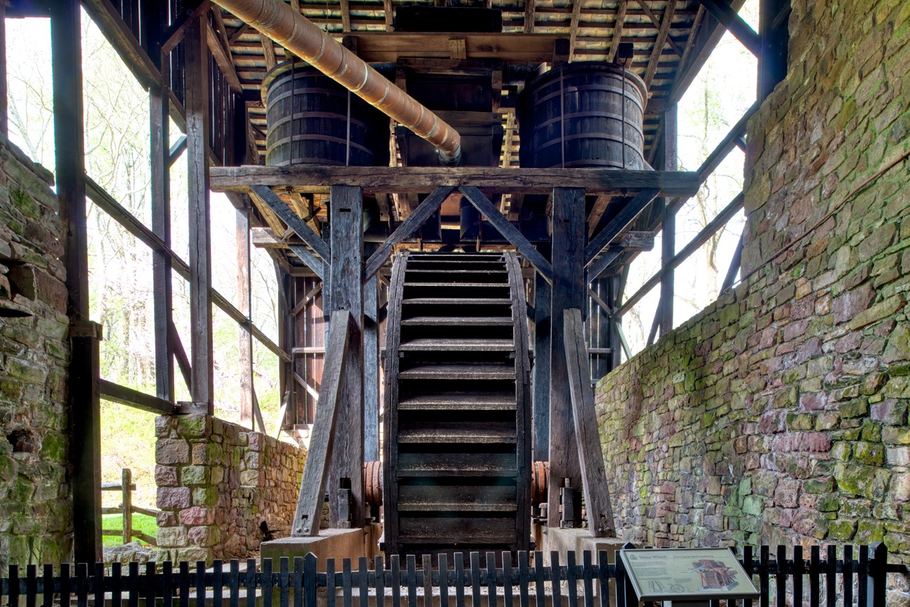 Wooden water wheel powers blast machinery.