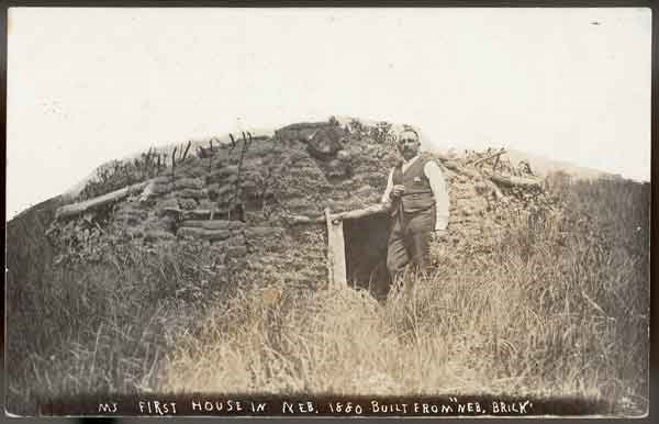 Solomon Butcher standing in front oh is first Nebraska house; a sod house