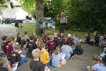 Ranger talking, with children seated in shade