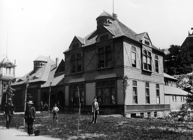Old wooden Lamar Bathhouse in 1889 with several figures standing out front.