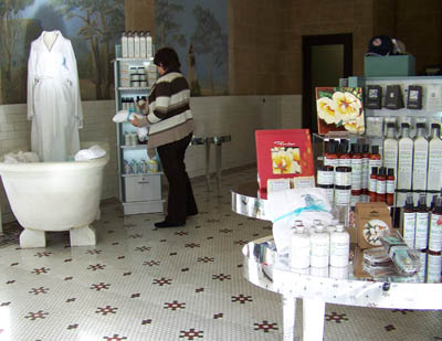 woman browses in store in background while low shelving with spa products is in foreground.