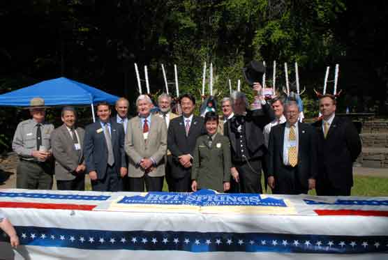 The following are standing behind a large rectangular birthday cake that has red and blue stripes on each end with the anniversary logo in the center: Asst. Superintendent Dale Moss, Midwest Regional Director Ernest Quintana,	Congressional staffer (for Mike Ross) Jeff Weaver, NPS Deputy Director Daniel Wenk,	Hot Springs Mayor Mike Bush, Arkansas State Rep. Gene Shelby, Hanamaki, Japan, Mayor Mitsuo Oishi, Park Superintendent Josie Fernandez, Arkansas State Rep. Bill Sample, President Andrew Jackson (Re-enactor Dave McArdle), Congressional staffer (for Blanche Lincoln) Ed French, Garland County Judge Larry Williams, Congressional staffer (for Mark Pryor) Robbie Reed