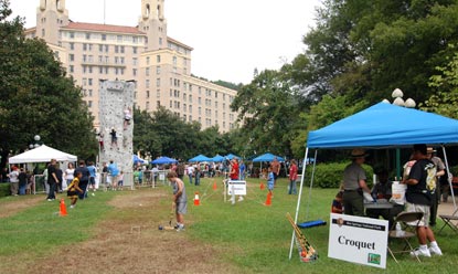 Large lawn area with blue canopies set up, one is in right foreground with sign that says