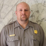 Portrait of ranger in uniform: white male with light brown facial hair and very short light brown hair, solemn look