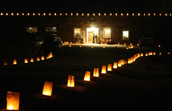 Luminarias outline the pathway and roof of the trading post.