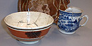 A redware plate with a yellow design, a blue and white Chinese teacup, and a brown and white bowl were found in pieces