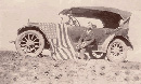 Sepia tone historic photograph of Homer Farr sitting on the running board of his flag draped Model T. Sepia tone historic photograph of Homer Farr sitting on the running board of his flag draped Model T.