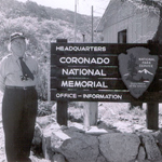 Grace M. Sparkes stands beside headquarter building and sign