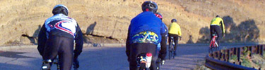 Color photo of 4 bicyclists riding up the road to the top of Capulin Volcano.