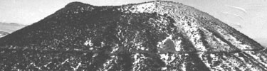 black and white photograph of volcano showing road and erosion channels