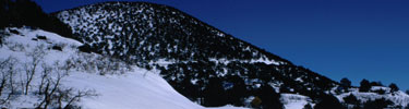 color photograph of deep snow with snow covered Capulin Volcano in background.