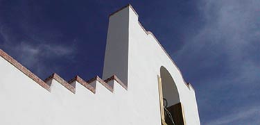 Mission style church with hanging bell glistens in bright sunshine