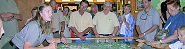 park ranger giving interpretive program to crowd of visitors around a map of the park.