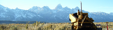 Road repair equipment at Blacktail Butte trailhead, with Tetons in background