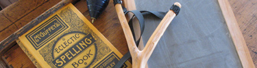 A McGuffey's Spelling Book, Spinning Top, Slingshot, and Slate sit on a desk in the Junction School