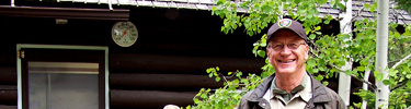 A photo of a volunteer in front of a cabin.