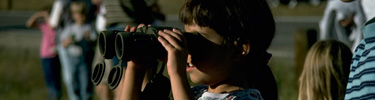 a photo of a small child looking through big binoculars