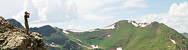 A photo of a biologist looking for bighorn sheep through binoculars.