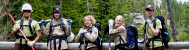 A photo of youth corps members on a log trail bridge.