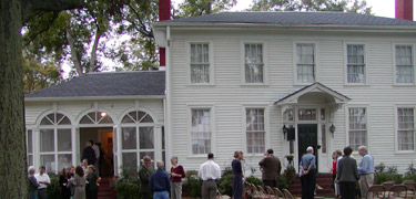 A group of people stand in front of a two-story frame house, home to Major Ridge in Rome, Georgia