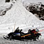 A snowmobile is parked next to a small snow slide.