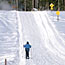 A cross country skier travels down a groomed trail.