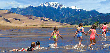 Children in Medano Creek with Dunes and Mount Herard