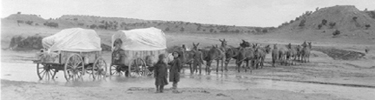 Two wagons crossing the wash toward Hubbell Hill.