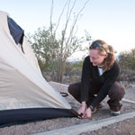 Woman stakes down a tent.