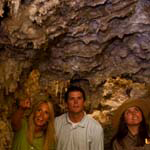A ranger and two visitors marvel at the ceiling of Chimes Chamber which is covered with cave formations.