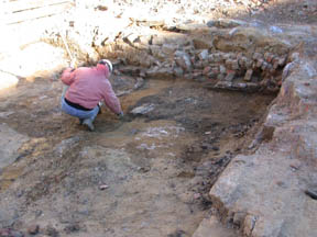 Photo of Archeologist towel-scraping the soil.