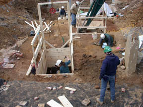 Photo of archeologists excavating a deep brick lined privy shaft.
