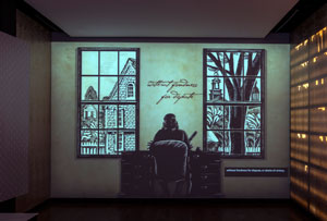 Screen view of the computer animation showing Benjamin Franklin seated at a desk writing his autobiography.