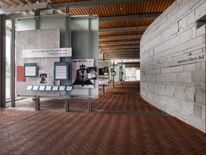 Exhibits about the Liberty Bell line the left side of a long, narrow hallway in the Liberty Bell Center.