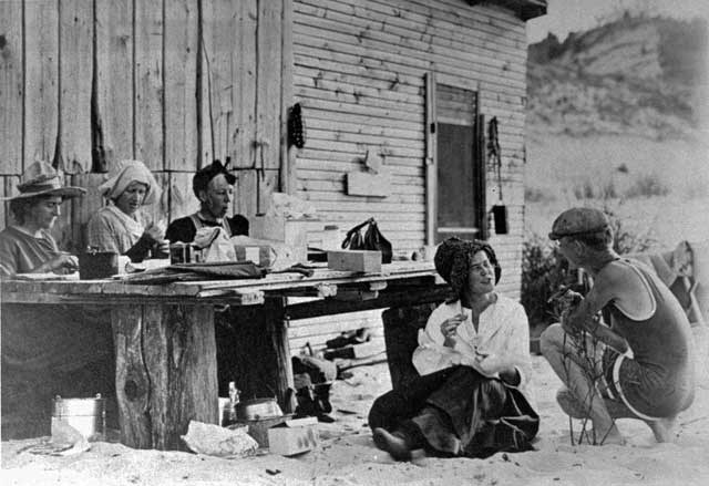 Prarie club members sitting outside of a cabin.