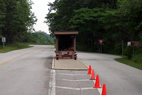 road with small building in the middle for cars to stop at