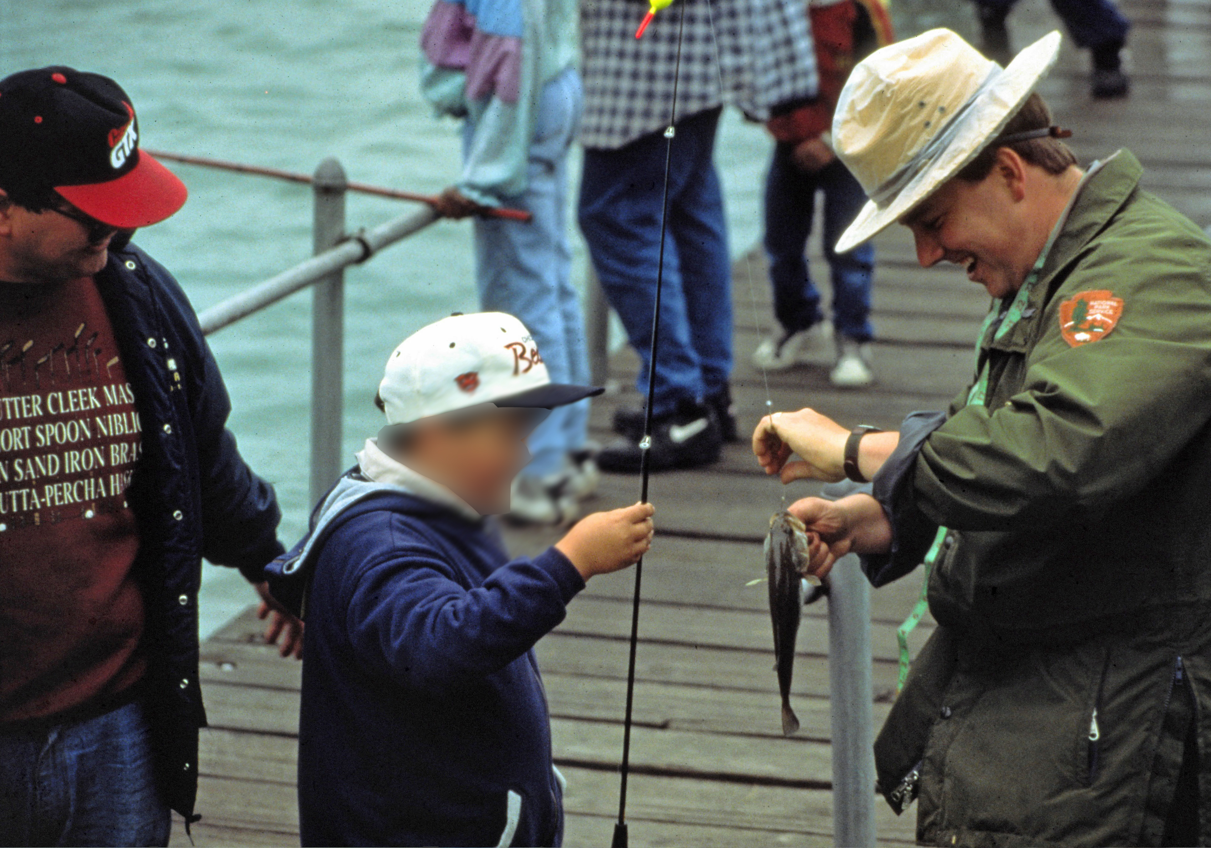 A ranger assists a young boy with unhooking his fish.