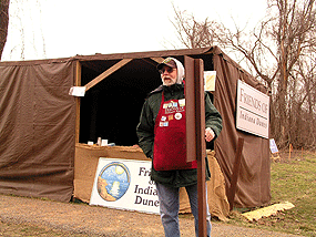 Man standing in front of a booth that has the words Friends of the Dunes on it