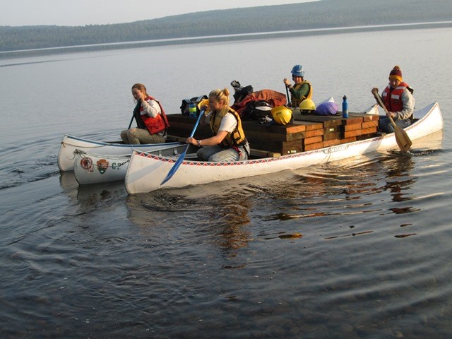 Trail Crew transports boards across Siskiwit Lake strapped to canoes.