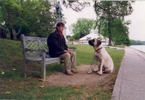 Visitor with dog on a leash resting along the Jamestown Seawall
