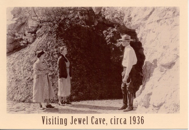 A Park Ranger and two visitors infront of the Historic cave entrance.