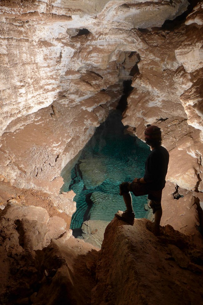 A caver standing in front of a Cave Lake