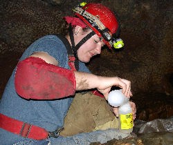 A physical science intern takes a water sample inside the cave