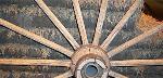 Wagon wheel with sod bricks in background