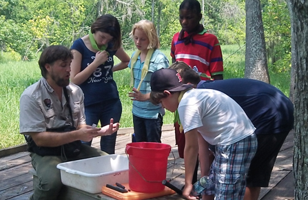 Image of young people and National Park Service biologist looking at specimens