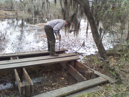 Image of man working on a wooden platform that will become a canoe dock